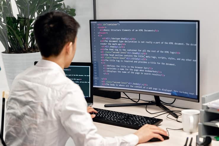 Information technology student writing code at a desktop computer